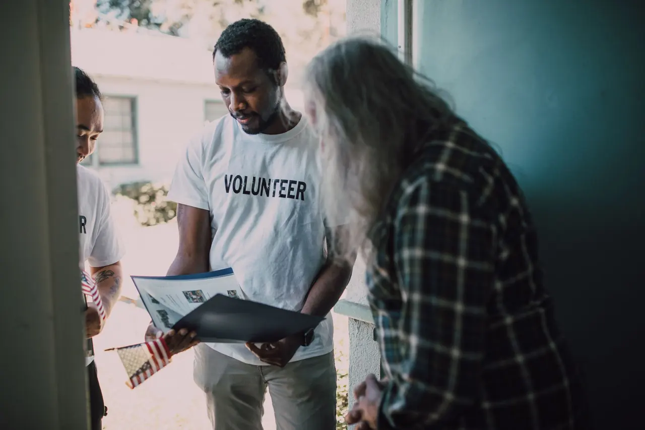 A volunteer sharing information with a resident at the door