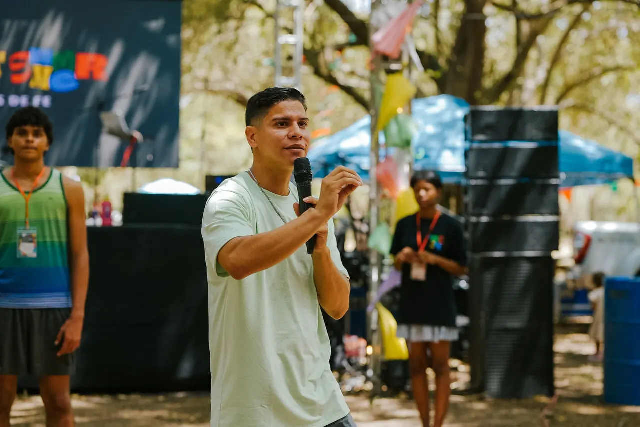 A community organizer speaking into a microphone at an outdoor event